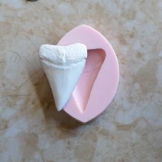 a toothbrush shaped like a piece of paper on top of a pink object with a hole in the middle