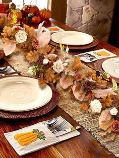 the table is set for thanksgiving dinner with white plates and silverware, fall flowers and pumpkins