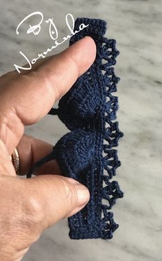 a hand is holding two crocheted pieces of cloth