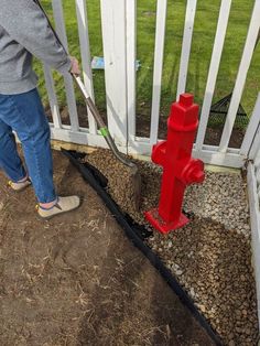 a person using a hose to fix a fire hydrant on the side of a fence