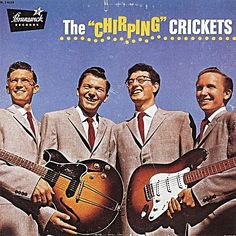 three men in suits and ties are holding two guitars while one man is smiling at the camera