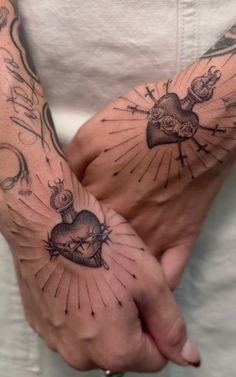 two people with tattoos on their arms holding each other's hands in the shape of hearts