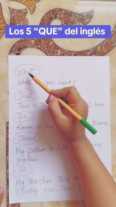 a child's hand holding a pencil writing on a piece of paper with the words los 5 que del ingles