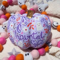 a purple pumpkin sitting on top of a pile of pom poms next to stuffed animals