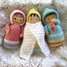 three knitted dolls sitting on top of a white doily