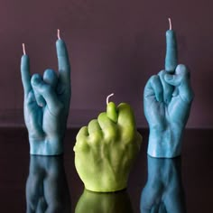 two hands holding candles in the shape of fingers, with one hand pointing up at the other