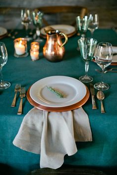 a table set with plates, silverware and candles