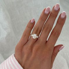 a woman's hand with a ring on top of her finger and a pink manicure