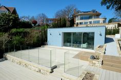 an outdoor deck with glass railings and steps leading to the back of a house