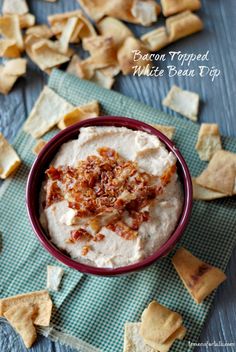 bacon topped white bean dip in a bowl surrounded by crackers