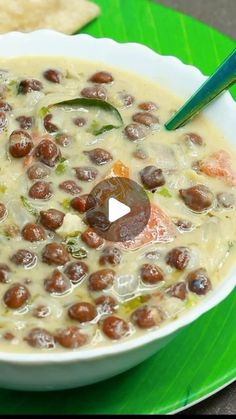 a white bowl filled with beans and vegetables on top of a green leafy plate