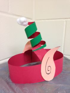 a pink paper boat with a green and red hat on top