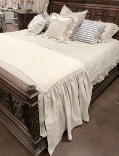 a bed with white sheets and pillows on top of it in a room filled with furniture