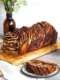 a loaf of chocolate marbled bread on a wooden cutting board next to a vase with flowers