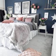 a bedroom with blue walls and white carpeted flooring is decorated in pink and grey tones