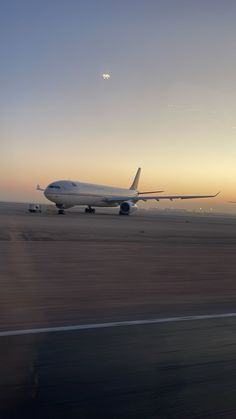 an airplane that is sitting on the runway at sunset or dawn, with it's landing gear down