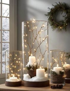 lighted candles and branches in glass containers on a table