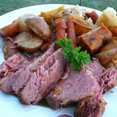 corned beef with potatoes and carrots on a white plate in front of a green lawn