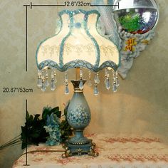 a blue lamp sitting on top of a table next to a vase filled with flowers