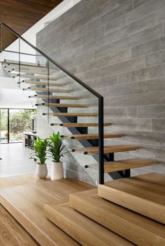 there is a stair case next to the stairs in this modern house with wood flooring and glass railings