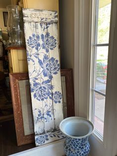 a blue and white vase sitting in front of a window