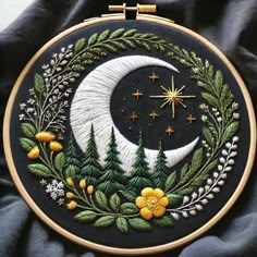 an embroidery project with a crescent and stars on the moon, surrounded by leaves and flowers