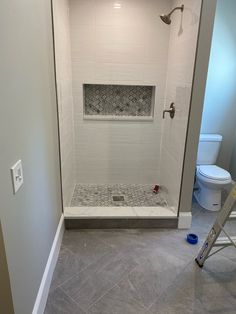 a bathroom with a walk in shower next to a white toilet and tiled flooring