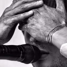 a man holding his hands to his head with a microphone in front of him and the other hand covering his face