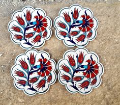 four red and blue plates sitting on top of a stone floor next to each other