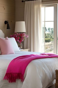 a bed with pink and white pillows in a bedroom next to a sliding glass door