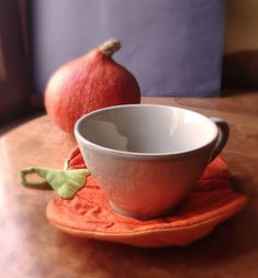 an orange and white bowl sitting on top of a wooden table next to two red apples