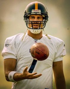 a man holding a football in his right hand and wearing a helmet on the other