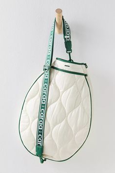 a white and green purse hanging from a hook on the side of a wall,