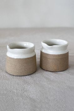 two white and brown vases sitting on top of a bed