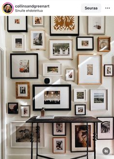 a room with many pictures on the wall and a table in front of it that is surrounded by framed photos