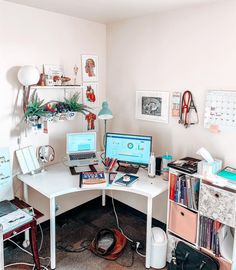 a computer desk with two laptops on top of it and various other office supplies