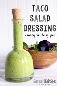 there is a green dressing in a bottle next to a bowl with salad on it