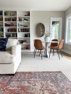 a living room filled with furniture and bookshelves next to a dining room table