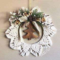 a christmas ornament hanging from the side of a wall with pine cones and evergreens