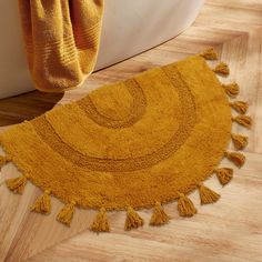 a yellow rug with tassels is on the floor next to a bathtub