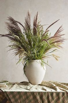 a plant in a white vase sitting on top of a checkered tablecloth covered table