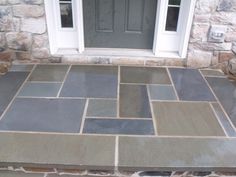 a front porch with flagstone and stone flooring on the side of the house