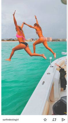 two women in bikinis jumping into the water from a boat