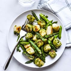 a white plate topped with asparagus and scallops