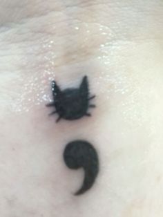 a small black cat on the side of a woman's chest with an upside down tail