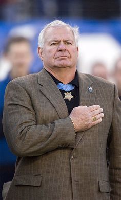 an older man in a suit standing with his arms crossed