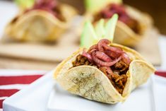 a taco filled with meat sitting on top of a white plate next to other food items