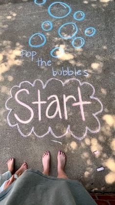 two people sitting on the ground with chalk writing in front of them and bubbles drawn on the pavement