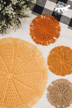 four different colored rugs sitting on top of a white tablecloth next to a potted plant