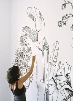 a woman is drawing flowers on the wall